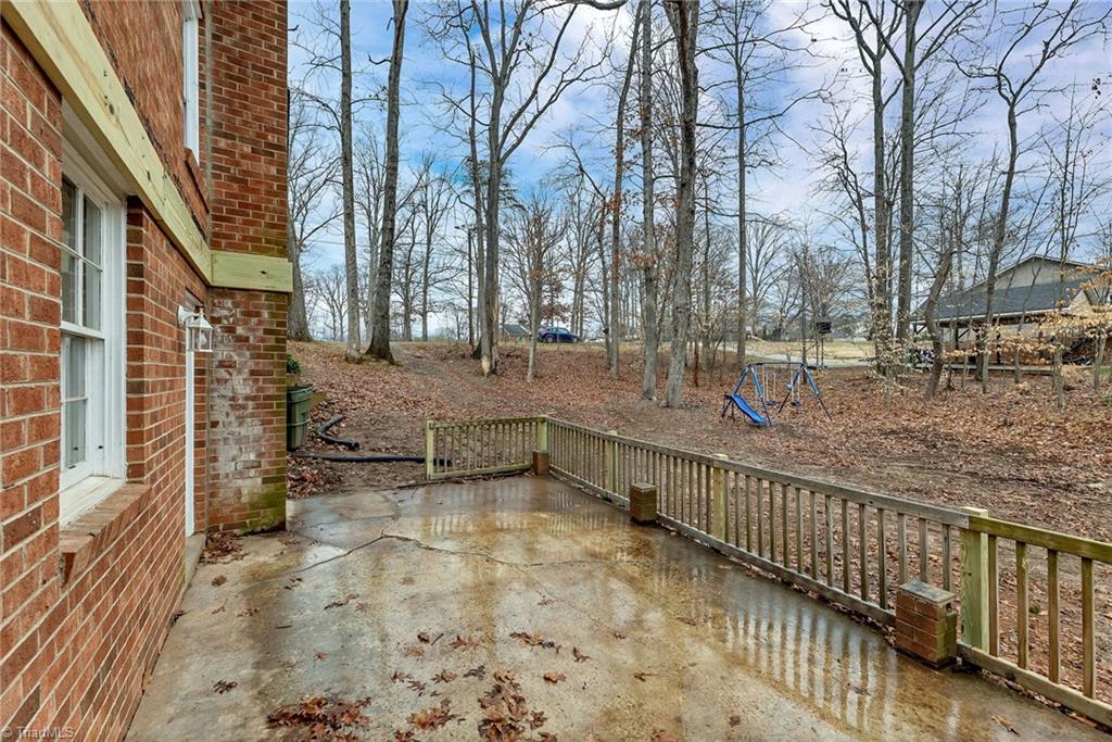 795 Dan Valley Road Madison, NC 27025 - Photo 38 of 38 Right side View looking from rear right to the front: Here we can see the updated side patio area and the side yard. You also have an entry door to the basement den area.