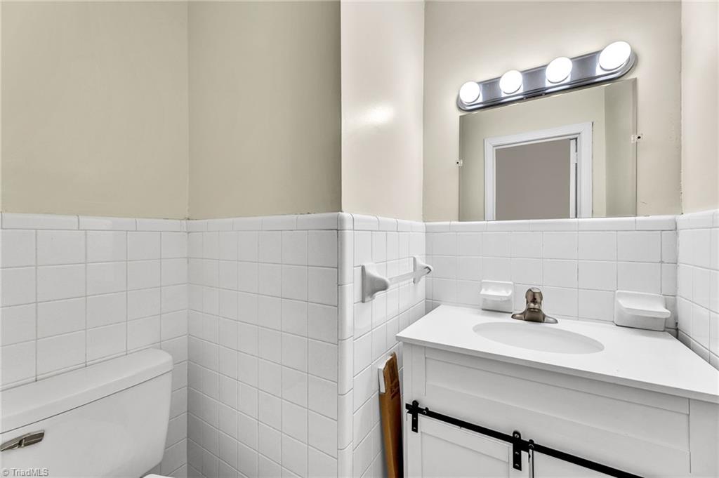 795 Dan Valley Road Madison, NC 27025 - Photo 6 of 38 Primary Half Bath: Features include vinyl flooring for easy cleaning and a bright vanity cabinet. Cabinet has a decorative sliding door.