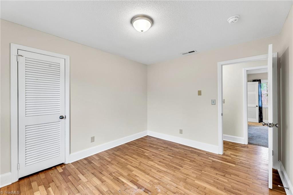 795 Dan Valley Road Madison, NC 27025 - Photo 9 of 38 Bedroom 3: Features include hardwood flooring for easy cleaning, a decorative chair rail to help protect the wall, wainscoting, a window for natural lighting and fresh paint. The closet is over to the left side.