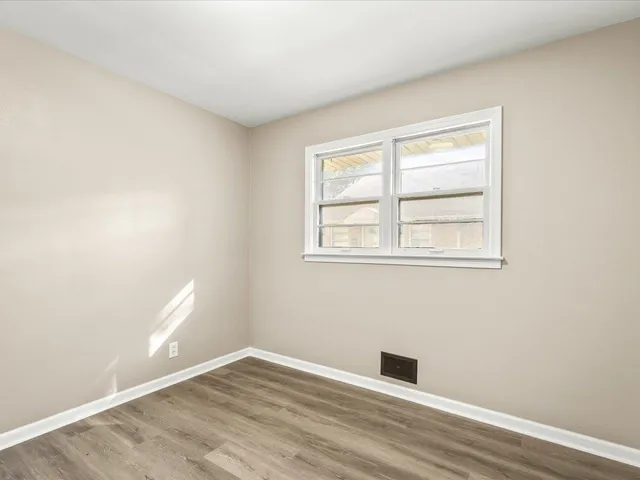 a view of an empty room with wooden floor and a bathroom