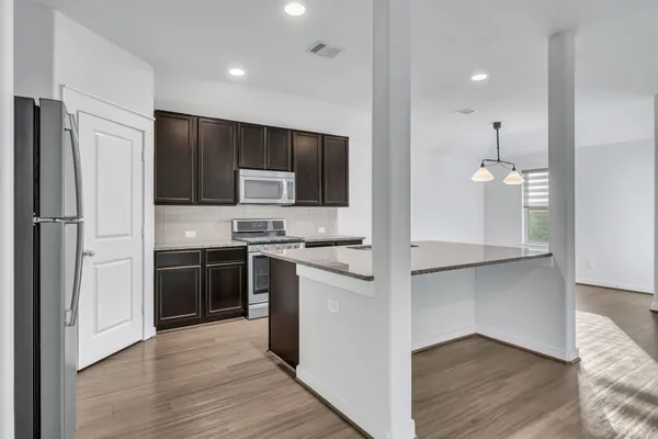 a kitchen with kitchen island a counter space a sink appliances and cabinets