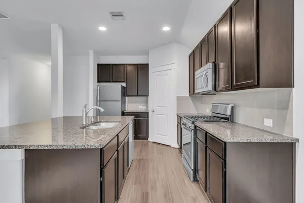 a kitchen with stainless steel appliances granite countertop a sink stove and cabinets
