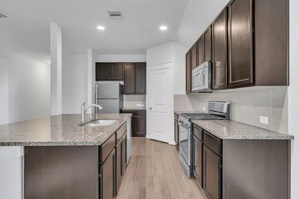 a kitchen with stainless steel appliances granite countertop a sink stove and cabinets
