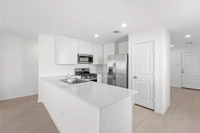 a kitchen with stainless steel appliances a refrigerator sink and microwave