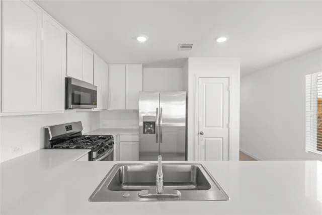 a kitchen with a sink a counter top space and stainless steel appliances