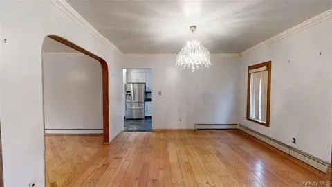 an empty room with wooden floor chandelier and windows