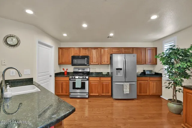 a kitchen with stainless steel appliances granite countertop a refrigerator a stove top oven a sink and dishwasher