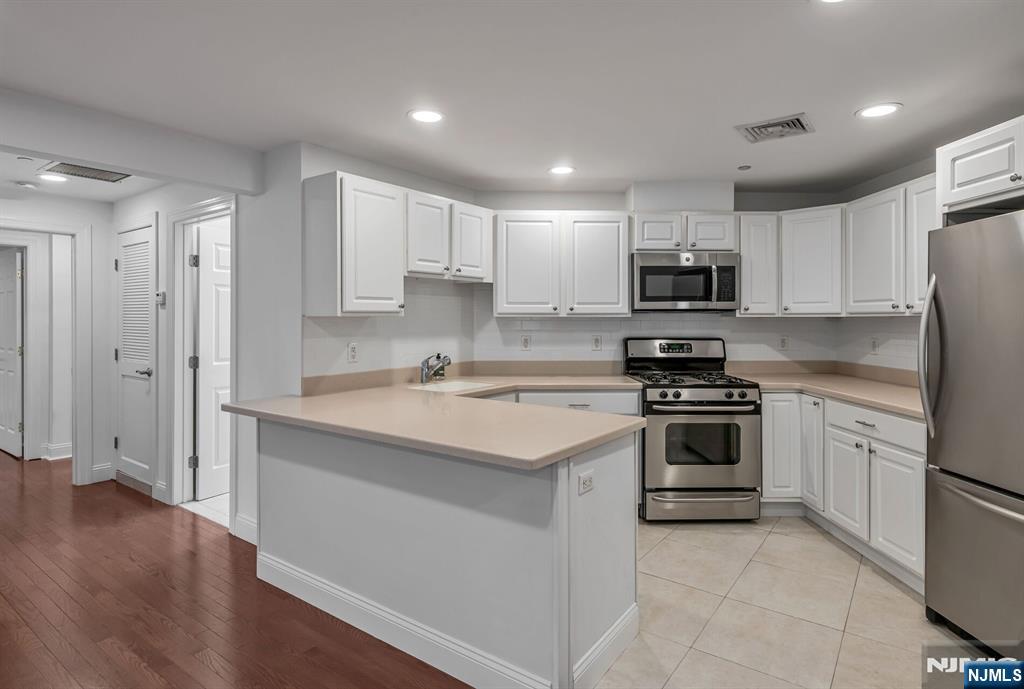 a kitchen with a sink white cabinets and stainless steel appliances