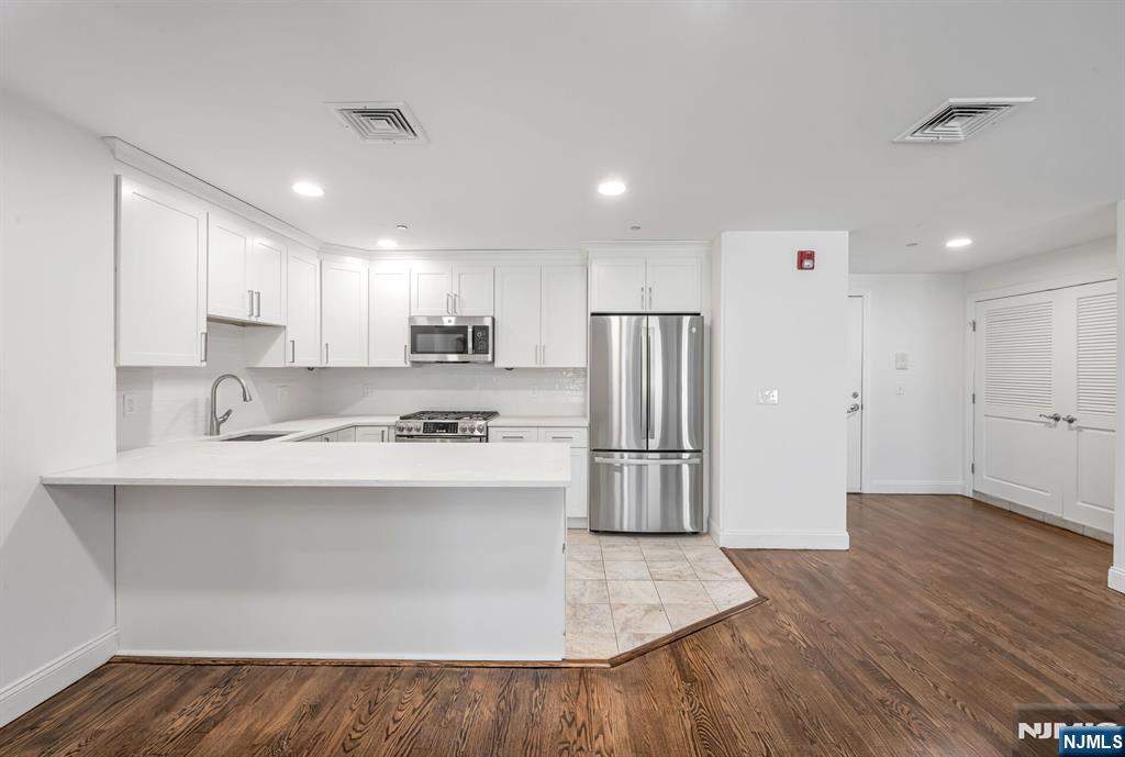 30 Jefferson Avenue, Unit C Westwood, NJ 07675 - Photo 4 of 9 a kitchen with stainless steel appliances granite countertop a refrigerator a sink dishwasher a oven with white cabinets and wooden floor
