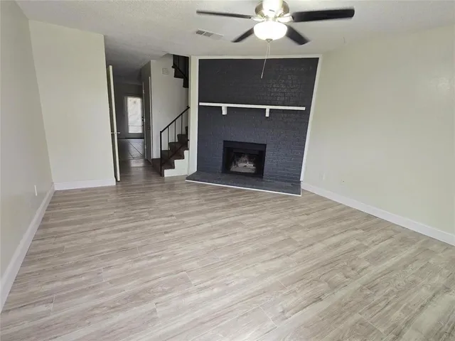a view of an empty room with wooden floor fireplace and a window