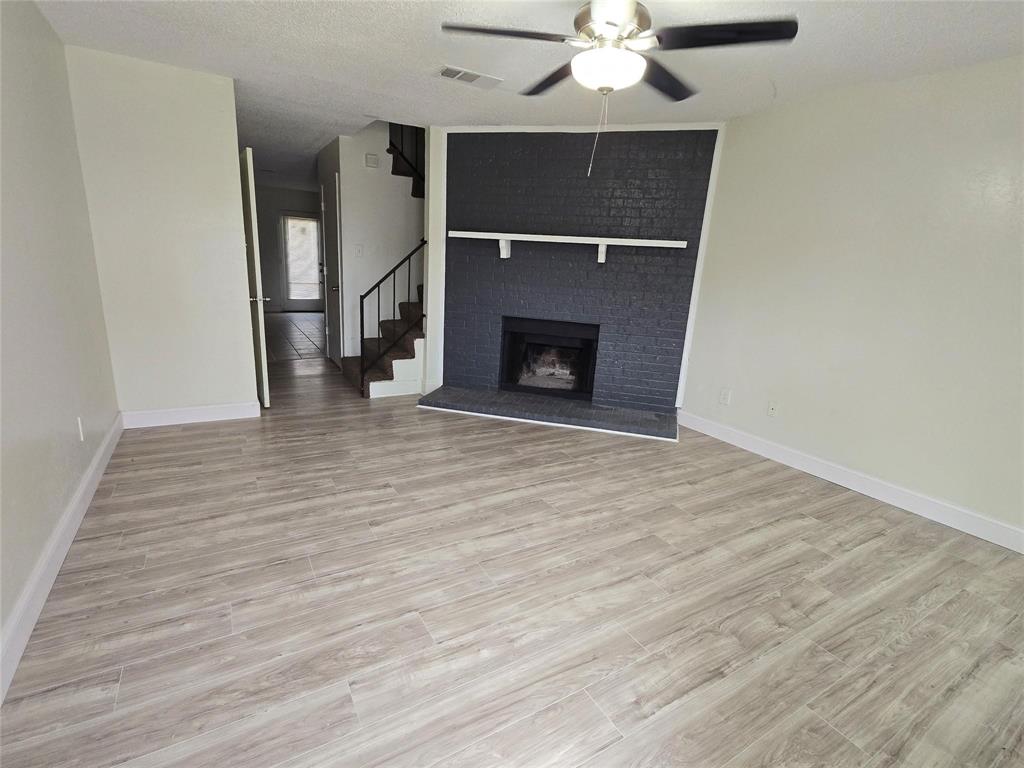10500 Lake June Road, Unit I03 Dallas, TX 75217 - Photo 2 of 11 a view of an empty room with wooden floor fireplace and a window