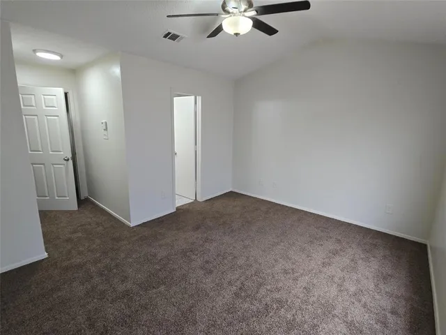 an empty room with fan walk in closet with window
