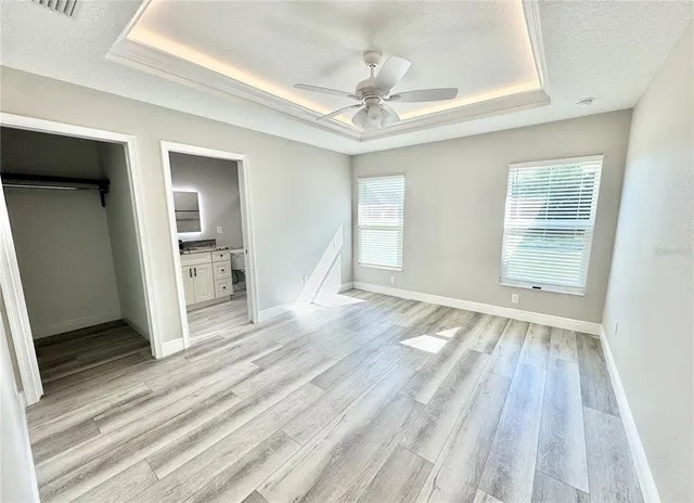 an empty room with wooden floor cabinet and windows