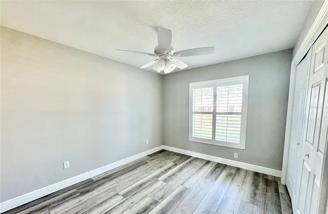 an empty room with a window and a ceiling fan