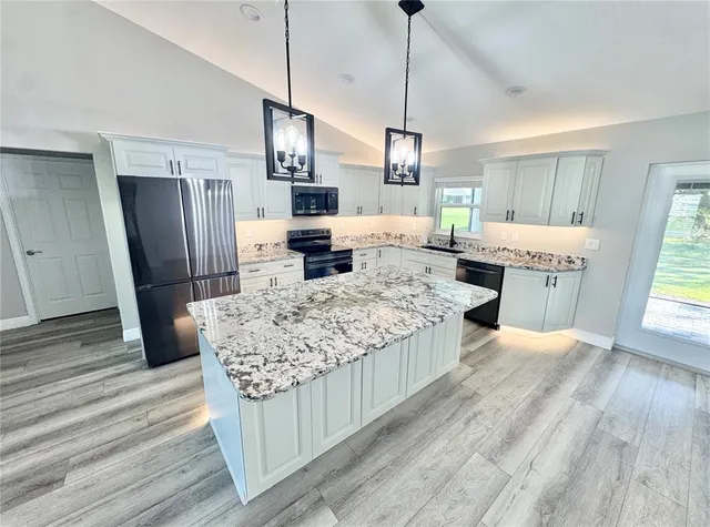 a large kitchen with kitchen island a counter space a sink appliances and cabinets