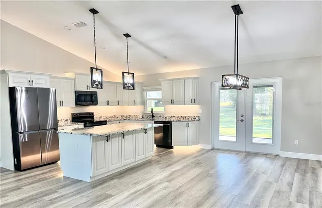 a kitchen with stainless steel appliances granite countertop a refrigerator a sink and a stove