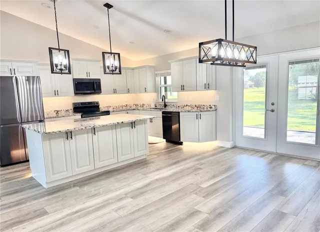 a kitchen with kitchen island granite countertop a stove a sink and a refrigerator