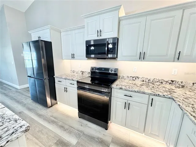 a kitchen with granite countertop a refrigerator stove and microwave