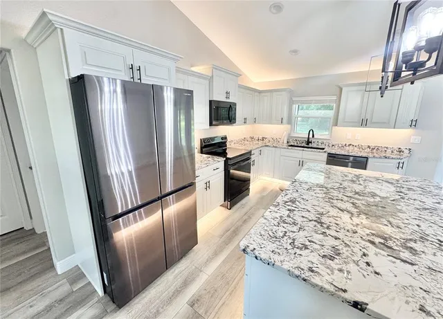 a kitchen with stainless steel appliances granite countertop refrigerator sink and microwave