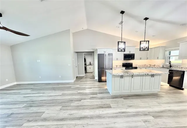 a kitchen with stainless steel appliances kitchen island granite countertop a stove a sink and a refrigerator