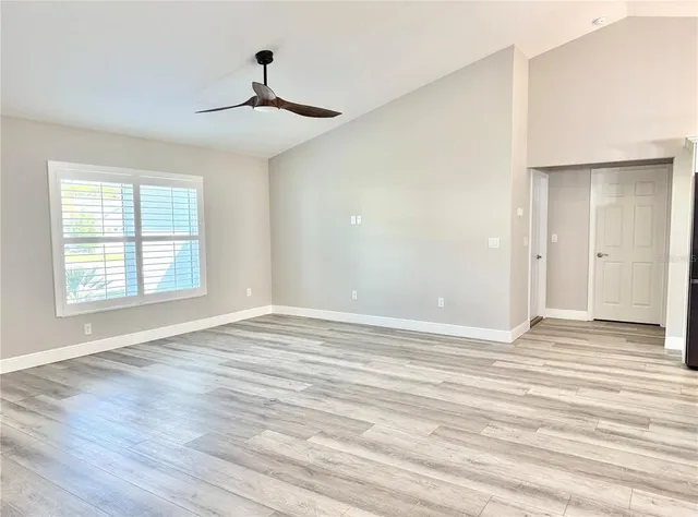 a view of an empty room with wooden floor and a window