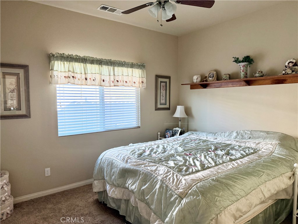 19422 Royal Oaks Road Apple Valley, CA 92308 - Photo 19 of 30 a bedroom with a bed and a chandelier