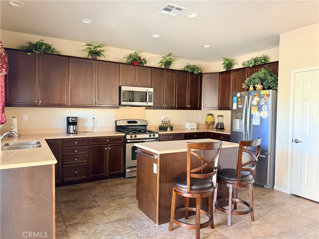 19422 Royal Oaks Road Apple Valley, CA 92308 - Photo 10 of 30 a kitchen with kitchen island granite countertop wooden cabinets and stainless steel appliances