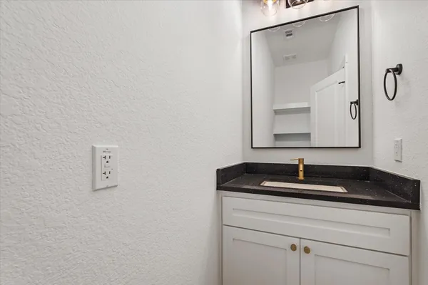 a bathroom with a granite countertop sink and a mirror