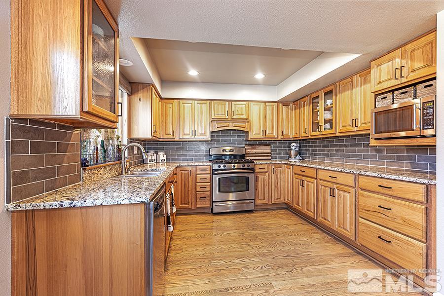14545 Ghost Rider Drive Reno, NV 89511 - Photo 7 of 24 a kitchen with stainless steel appliances granite countertop a stove sink and cabinets