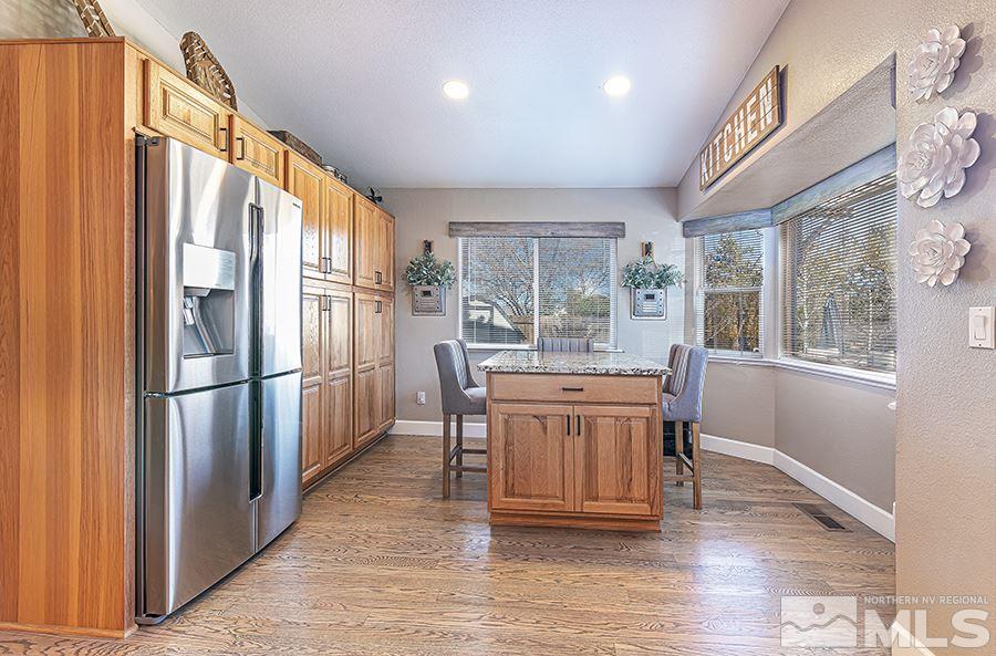 14545 Ghost Rider Drive Reno, NV 89511 - Photo 9 of 24 a kitchen with stainless steel appliances granite countertop a refrigerator a sink dishwasher a stove and a dining table with wooden floor