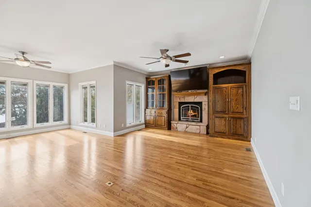 an empty room with chandelier fan and windows