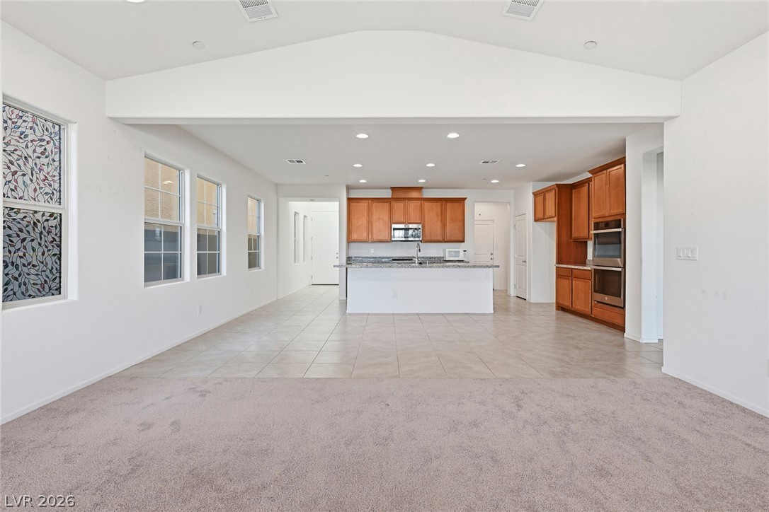 250 Dedication Avenue Henderson, NV 89011 - Photo 12 of 67 Unfurnished living room with recessed lighting, light colored carpet, light tile patterned flooring, and lofted ceiling
