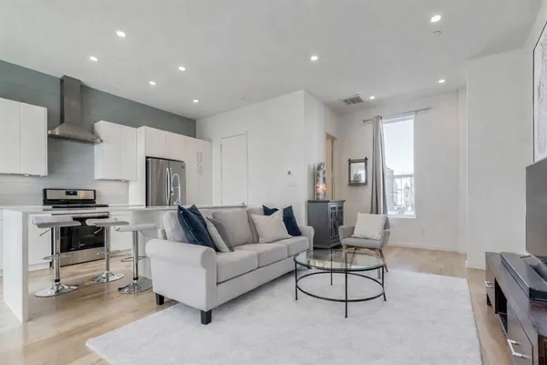 a living room with furniture a rug and kitchen view
