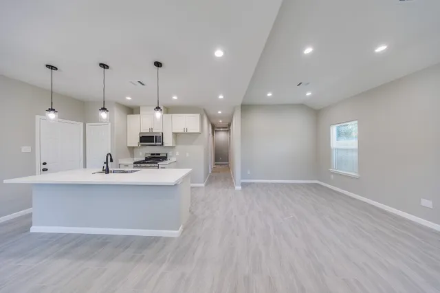 a view of a kitchen with kitchen island a sink wooden floor and a large window