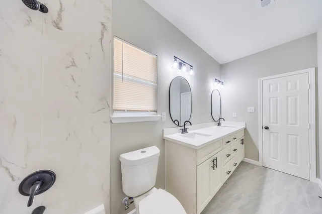 a bathroom with a granite countertop toilet sink and mirror