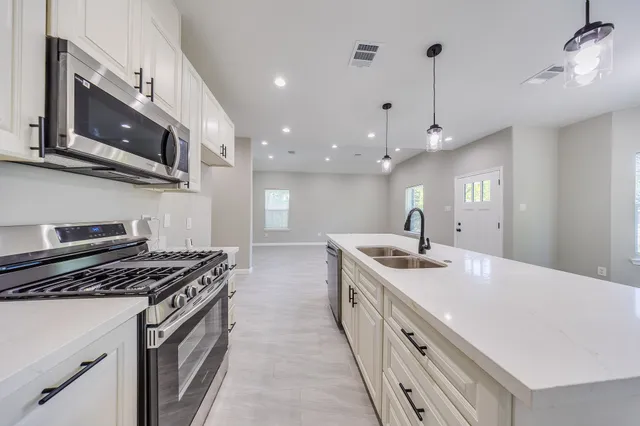 a kitchen with stainless steel appliances granite countertop a sink a stove and a wooden floors