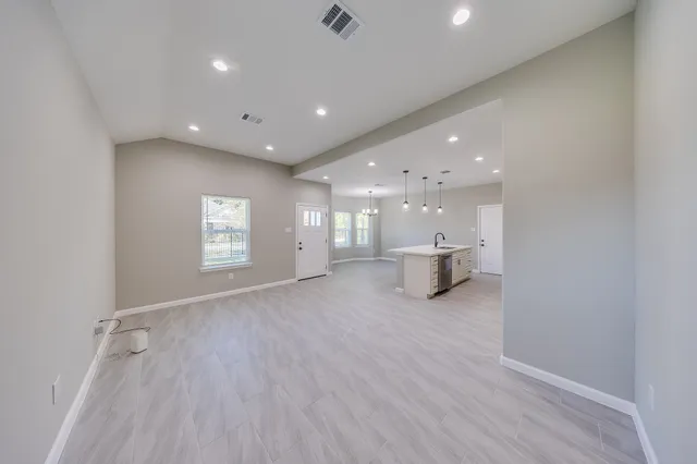a view of an empty room with window and wooden floor
