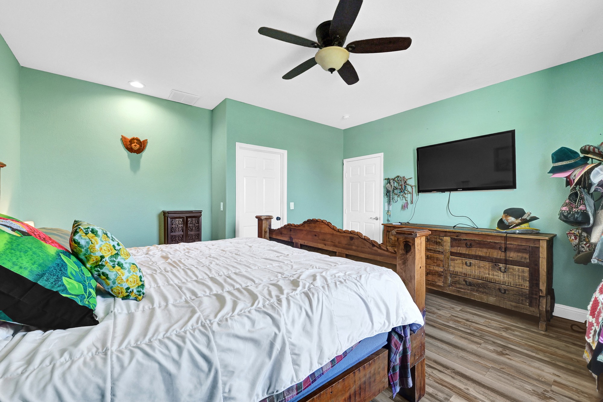 939 8th Street Dickinson, TX 77539 - Photo 17 of 31 This cozy bedroom features mint green walls, a ceiling fan, and wood flooring.