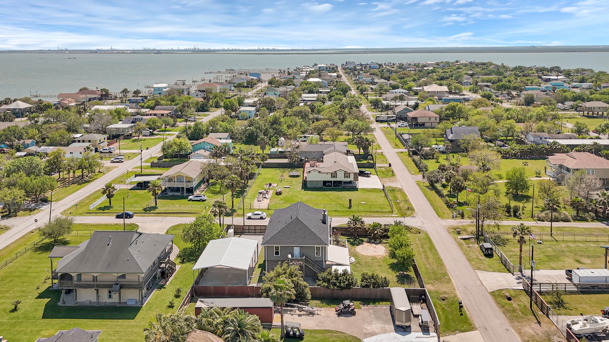 939 8th Street Dickinson, TX 77539 - Photo 19 of 31 This photo showcases the neighborhood with spacious homes and well-maintained yards, offering a serene setting close to the water. The streets are lined with greenery, and the view extends to the shoreline, indicating easy access to beachside activities.