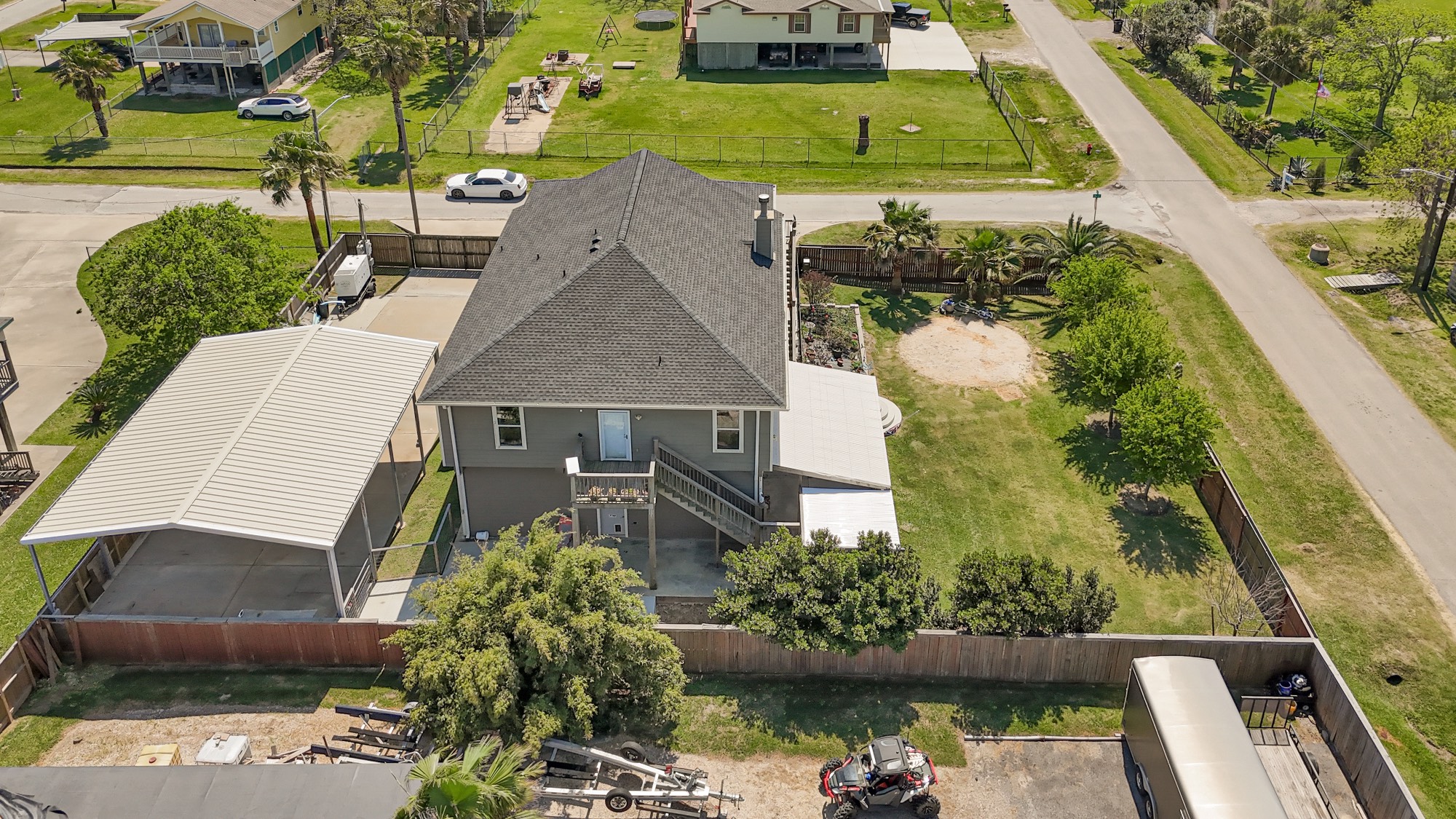 939 8th Street Dickinson, TX 77539 - Photo 21 of 31 This aerial photo showcases a spacious two-story home with a large, fenced backyard on a corner lot. The property features a covered carport, a well-maintained lawn, and mature trees, offering privacy and ample outdoor space.