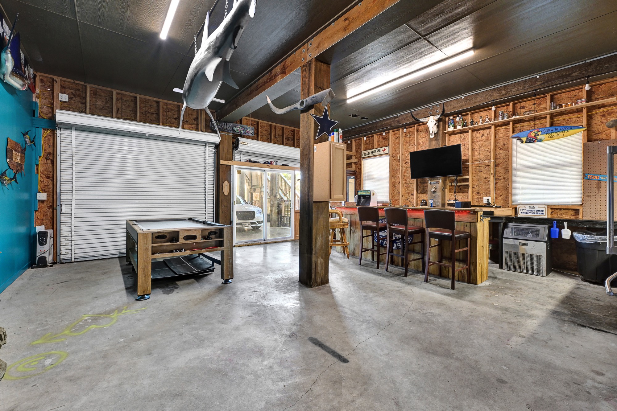 939 8th Street Dickinson, TX 77539 - Photo 30 of 31 This spacious garage features an entertainment area with a bar. The space is well-lit and has a roll-up door and sliding glass doors for easy access.