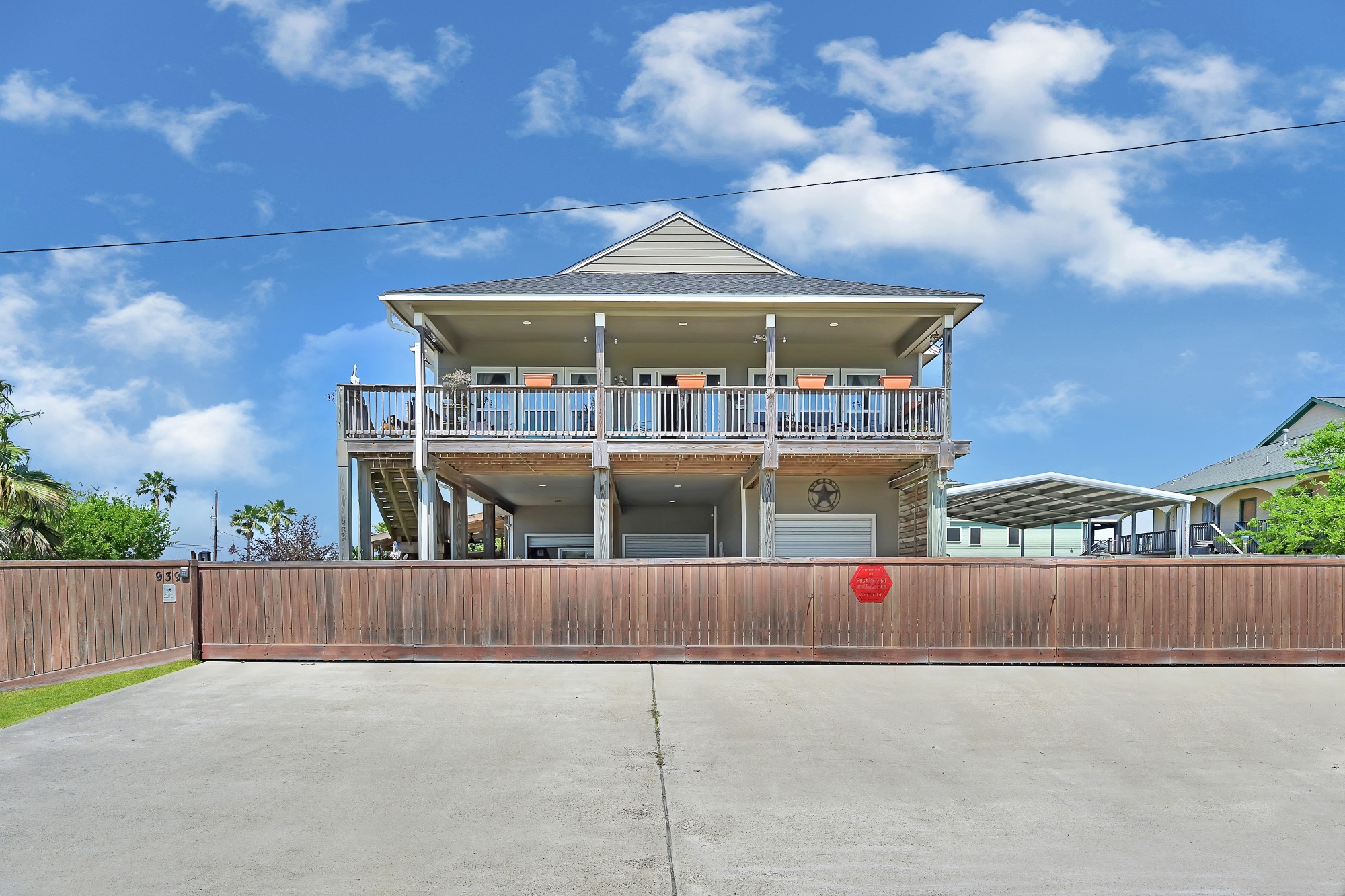 939 8th Street Dickinson, TX 77539 - Photo 4 of 31 This elevated home features a spacious wraparound balcony, a large gated driveway, and a carport. Its elevated design offers potential flood protection, and the wooden fencing provides privacy. Ideal for those seeking a blend of charm and functionality.