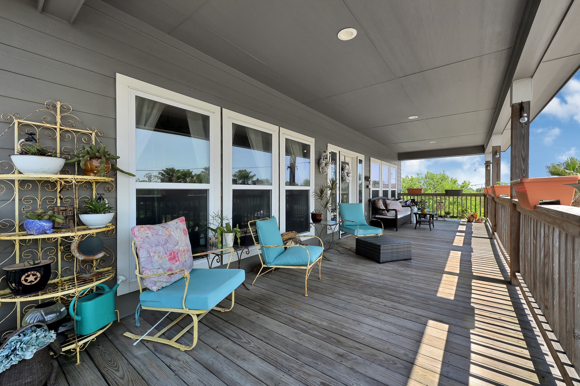939 8th Street Dickinson, TX 77539 - Photo 8 of 31 This photo showcases a spacious, inviting porch with ample seating, colorful decor, and lush greenery, perfect for relaxation and enjoying the outdoors.