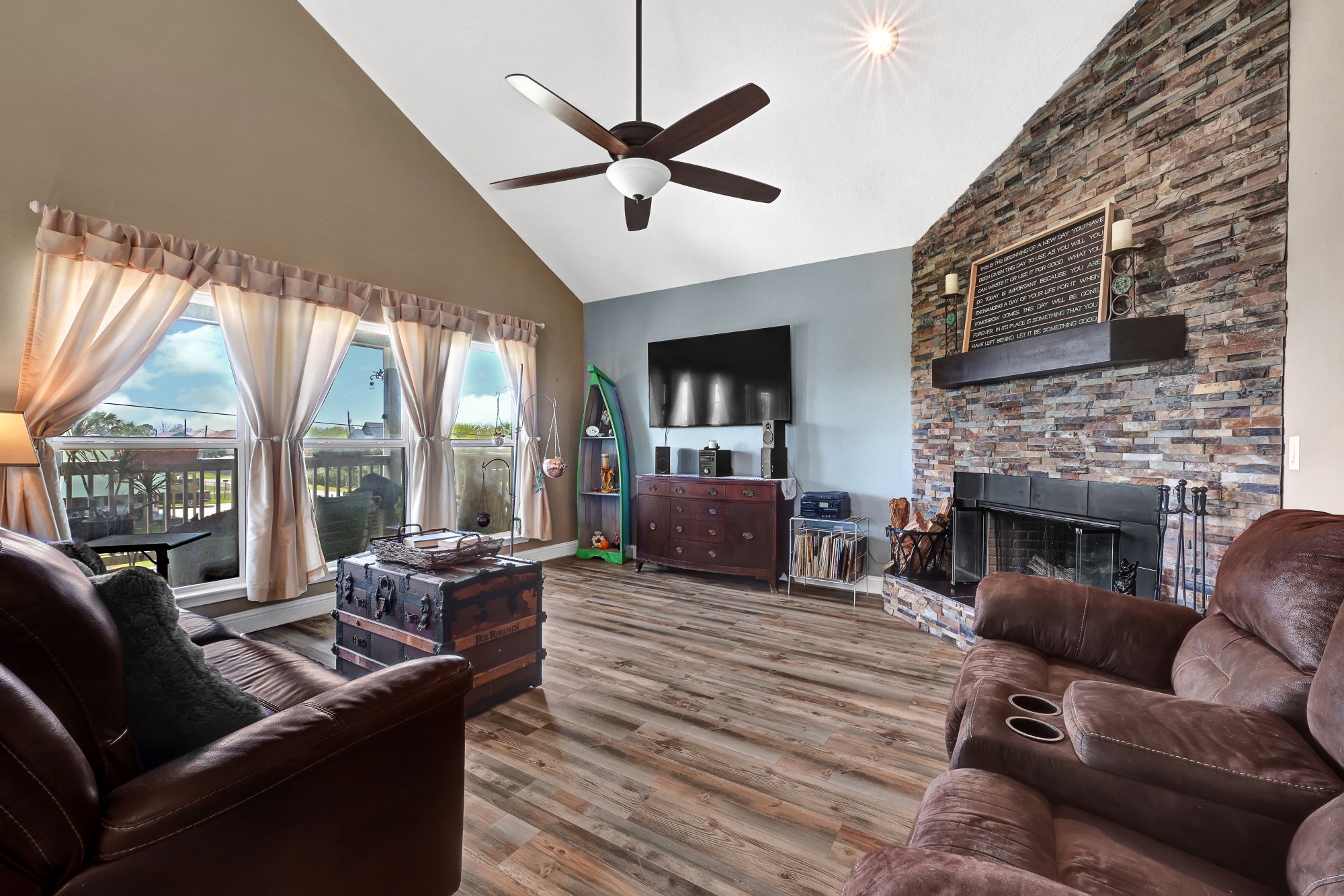 939 8th Street Dickinson, TX 77539 - Photo 9 of 31 Spacious living room with vaulted ceilings, large windows, and abundant natural light. Features a rustic stone fireplace and hardwood floors. Perfect for relaxation and entertaining.