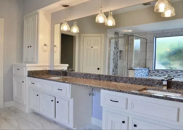 a bathroom with a granite countertop double vanity sink and a mirror