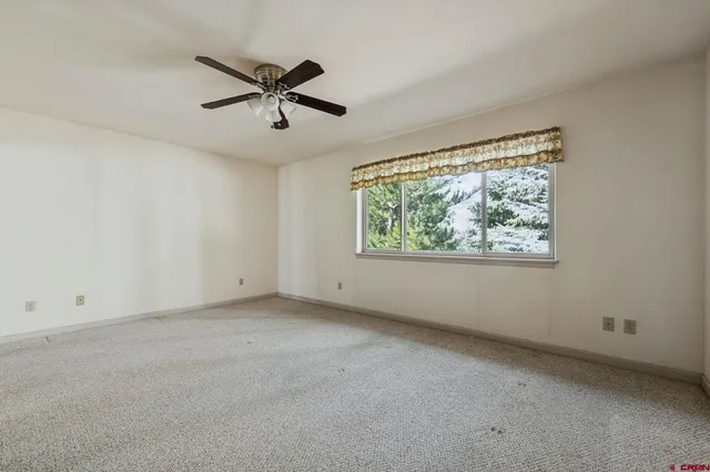 an empty room with ceiling fan and windows