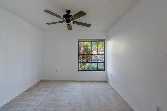 an empty room with a window and a fan