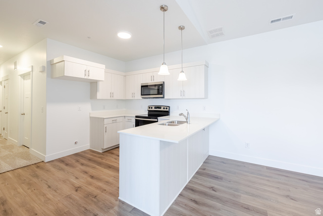 675 West 4500th South, Unit P301 Mapleton, UT 84664 - Photo 12 of 16 Modern kitchen featuring white cabinetry, light countertops, stainless steel appliances, a peninsula with pendant lighting, and wood-finish flooring