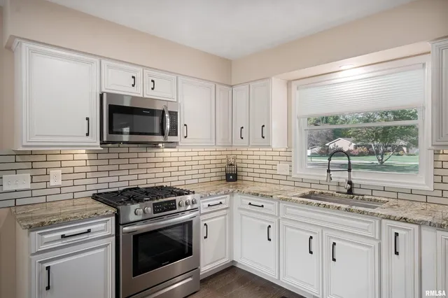 a kitchen with granite countertop white cabinets stainless steel appliances and a sink