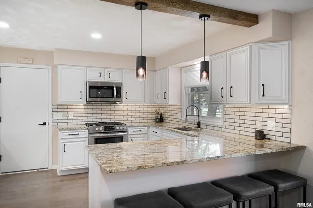a kitchen with kitchen island granite countertop a sink a counter space appliances and cabinets